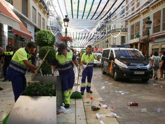 Operarios de limpieza recogen basura en Calle Larios.