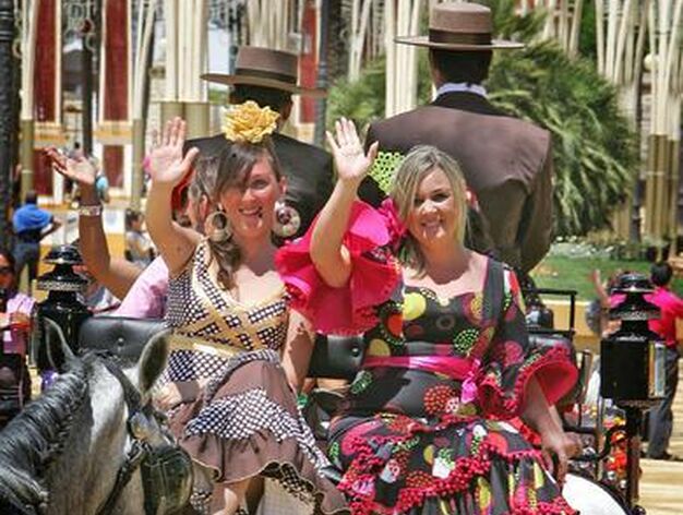 Dos j&oacute;venes vestidas de gitana saludan mientras dan un paseo en un coche de caballo, ayer, por el Real.

Foto: Pascual