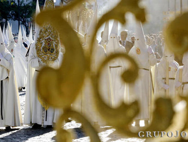 Las numerosas filas de nazarenos blancos de la hermandad del Transporte se adivinan entre las filigranas de sus insignias.

Foto: Miguel Angel Gonzalez