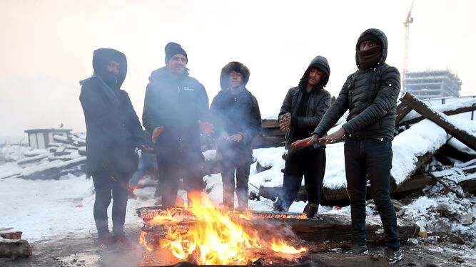 Varios refugiados  se protegen del frío  con una hoguera en Belgrado.