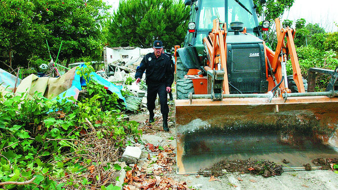 Un policía local avanza junto a una excavadora por los Huertos de Ocio en 2004.