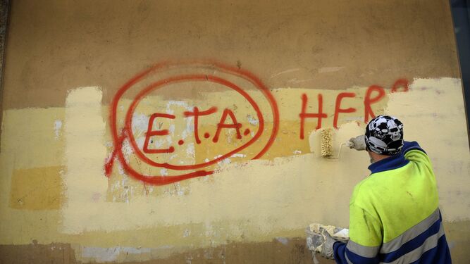 Un pintor municipal borra un grafiti que dice 'ETA'.