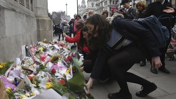 Varias personas depositan flores ayer ante el Parlamento por el ataque terrorista del pasado miércoles en Londres.