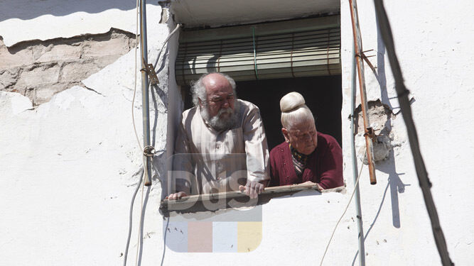 Dos vecinos miran desde una ventana el dispositivo desplegado tras el suceso.