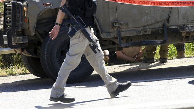 Imagen del detenido (tras el vehículo) por atropellar ayer intencionadamente a dos soldados israelíes en Cisjordania.