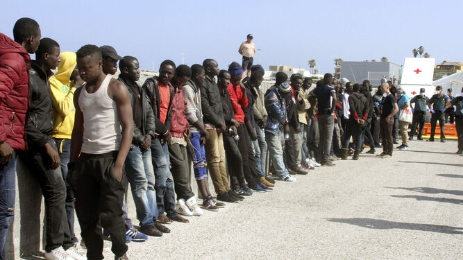 Un guardia civil y una sanitaria de la Cruz Roja dan indicaciones a varios inmigrantes en el puerto de Tarifa.