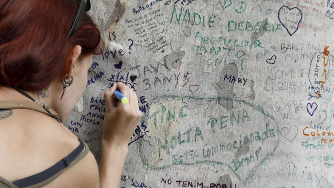 Una persona muestra sus condolencias con un mensaje escrito en un árbol de Las Ramblas.