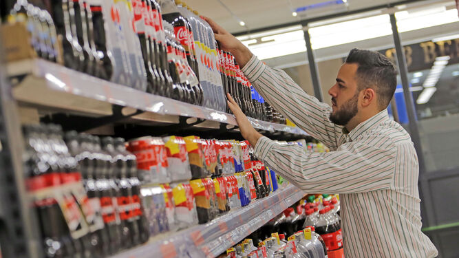 Un trabajador de una cadena de supermercados repone el lineal de las bebidas.
