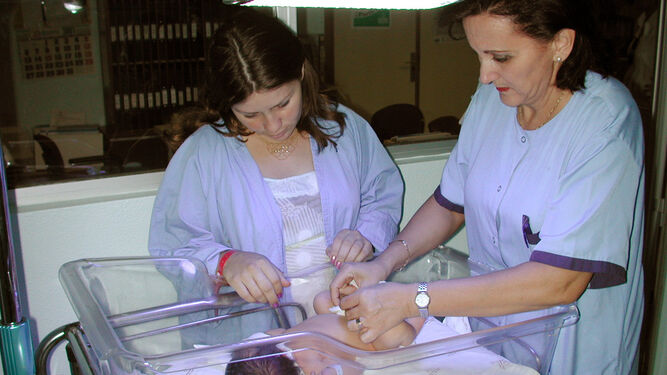 Una enfermera atiende a un recién nacido en presencia de su madre.