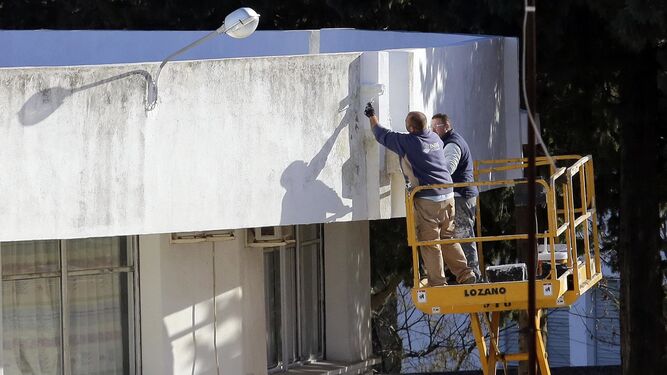 Dos operarios realizando labores de pintura en un edificio