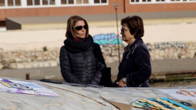 Dos mujeres junto a las flores y dibujos dejados en honor de Gabriel en Almería.