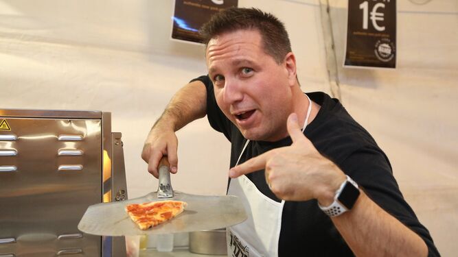 Un cocinero de uno de los once establecimientos que participan en el evento, mostrando una porción de pizza.