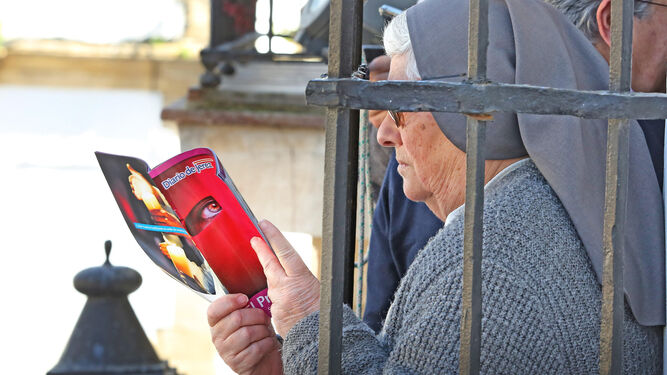 Una religiosa ojea la gu&iacute;a de Diario de Jerez mientras esperaba la salida de las Tres Ca&iacute;das en un balc&oacute;n de San Lucas.