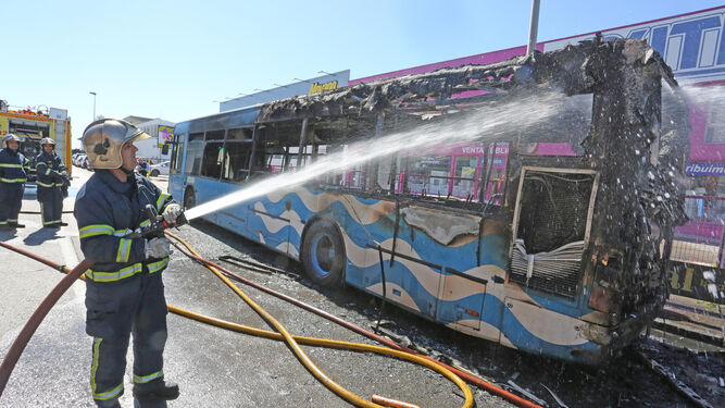 Los bomberos sofocan el autobús siniestrado, que quedó totalmente destrozado.