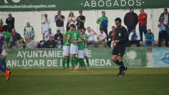Los jugadores del Sanluqueño se abrazan tras anotar uno de sus goles en El Palmar ante el Ciudad de Lucena.