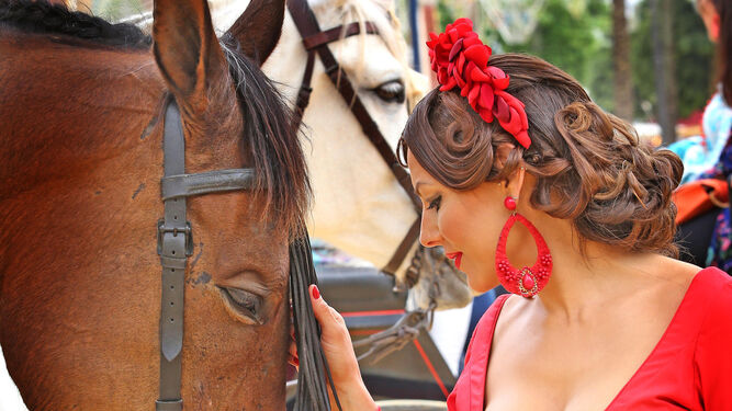 Una mujer acaricia el mosquero de un caballo en el Real de la Feria, ayer.