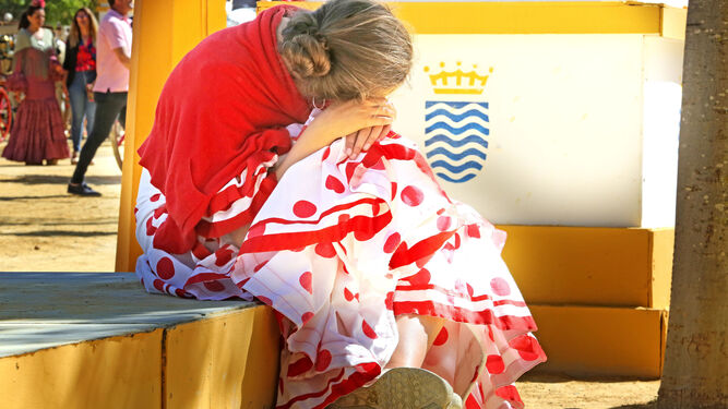 Una joven apoya su cabeza en sus rodillas en un signo de cansancio.