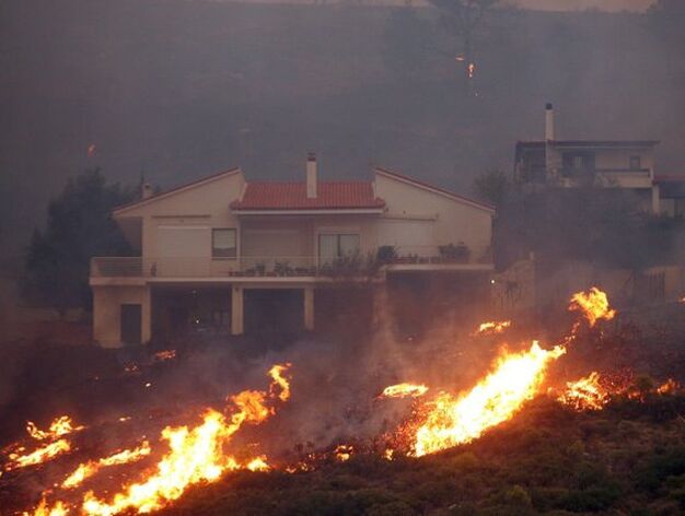 Las llamas rodean una casa en la localidad griega de Anthousa donde el incendio ya ha calcinado decenas de viviendas.

Foto: Efe