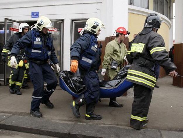 Los bomberos trasladan un cad&aacute;ver. / Reuters