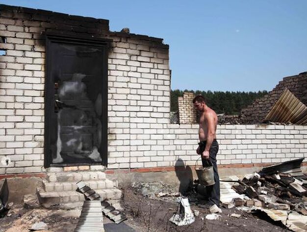 Un hombre mira su casa arrasada por las llamas. / AFP