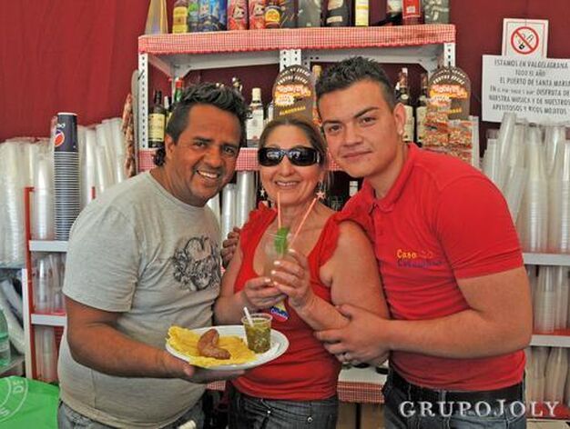 Tres de los camareros de la caseta Casa Colombia posan con una tapa de chorizo colombiano con arepa, una especie de torta de ma&iacute;z.

Foto: Manuel Aranda