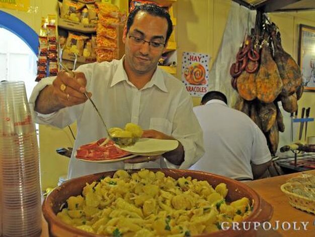 Uno de los camareros de la Casa de Extremadura sirve una tapa de papas ali&ntilde;adas a uno de sus clientes.

Foto: Manuel Aranda