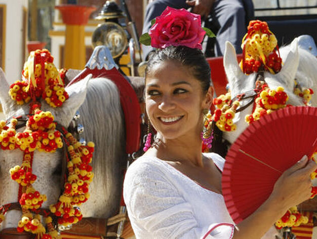 Colores vivos. Una bella flamenca sonr&iacute;e mientras se abanica junto a un coche de caballos, ayer, en la Feria.

Foto: Pascual