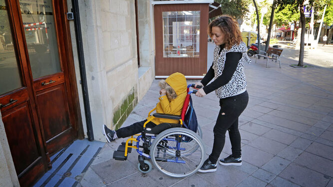 Lorena Moreno  empuja la silla de ruedas de su hijo.