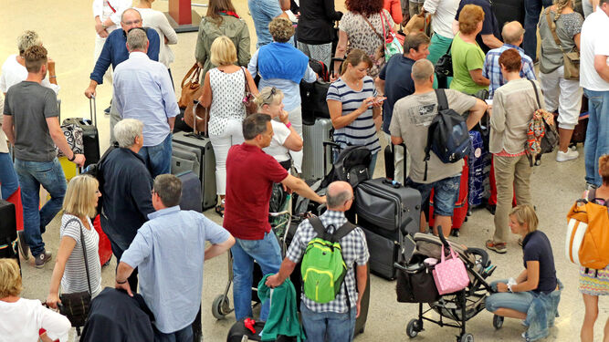 Turistas extranjeros haciendo cola en uno de los mostradores del aeropuerto para embarcar.