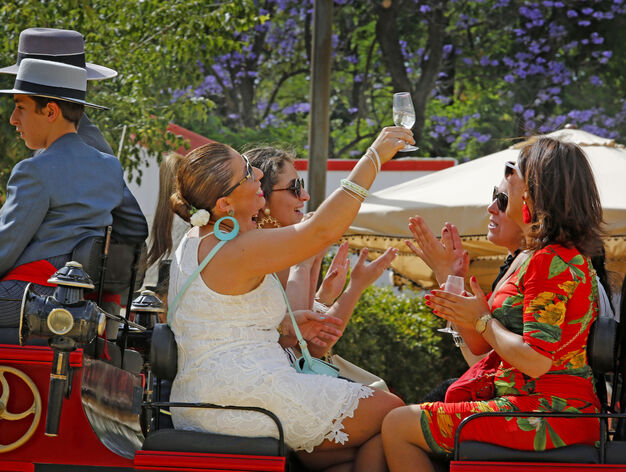 Dos mujeres se refescan con una bebida durante el paseo de caballos del Real.