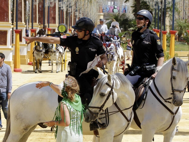 Polic&iacute;as a caballo ayudan a una mujer a encontrar una de las casetas en el Real.