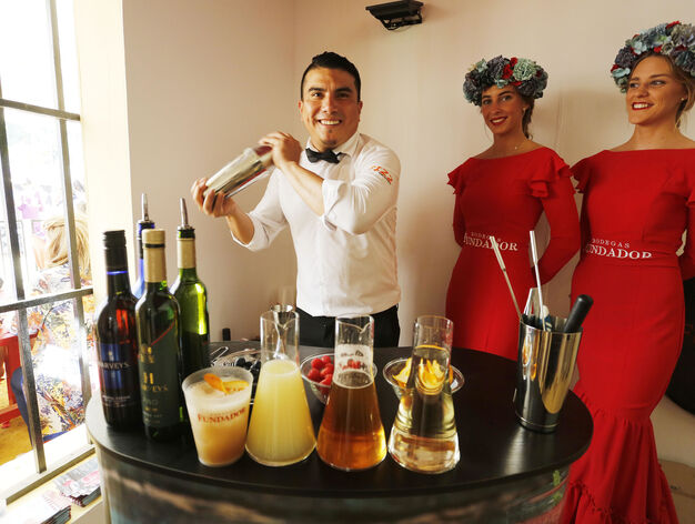 Ricardo Gonz&aacute;lez, bartender de FIZZ, elabora uno de los c&oacute;cteles de Harveys junto a dos azafatas de Fundador en la caseta de la bodega en la Feria.