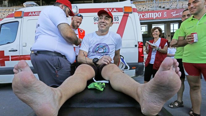 Humberto Otero, agotado pero sonriente, recibe ayer asistencia por problemas en su pierna izquierda.