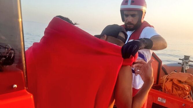 Un miembro de Cruz Roja atiende a dos menores magrebíes rescatados de una piragua.