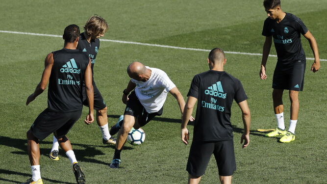 Zidane intenta robarle el balón a Modric en un rondo, entre Varane, Benzema y Asensio.