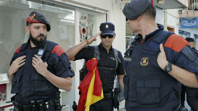Un agente de la Policía Nacional saluda a dos 'mossos' al despedirse tras dejar los hoteles de la localidad de Pineda de Mar tras varios escraches.
