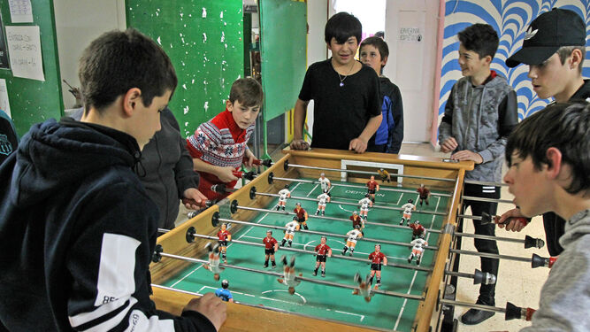 Niños juegan al futbolín en la sala de ocio de la asociación.