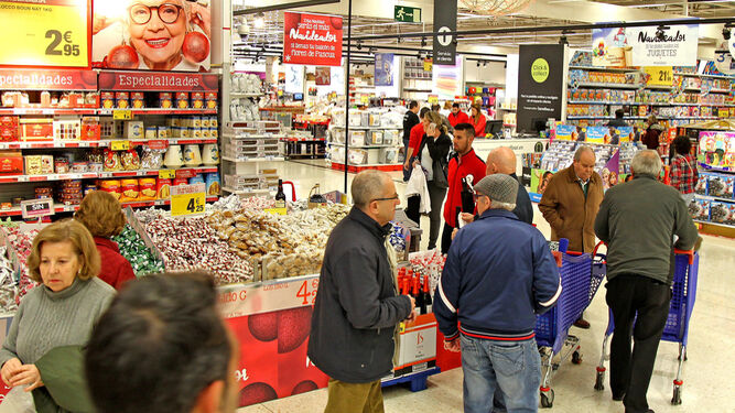 Consumidores pasan en un supermercado junto a una promoción de productos navideños.