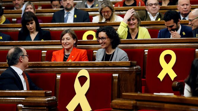 La presidenta del Parlament, Carmen Forcadell (i), y la secretaria general de ERC, Marta Rovira (d), rodeadas por varios escaños vacios adornados con lazos amarillos en recuerdo de los diputados electos encarcelados y huidos.