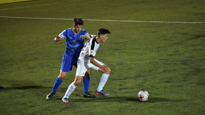 Javi Gómez encima a un jugador del Ceuta para evitar que progrese con el balón.