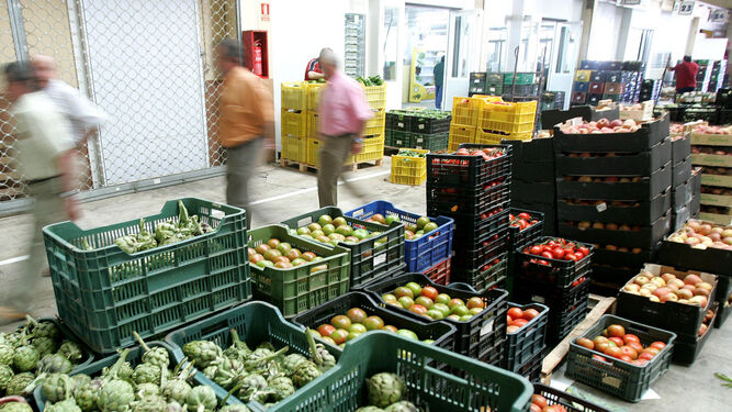 Clientes pasan ante cajas de frutas y verduras en las instalaciones de Mercajerez.