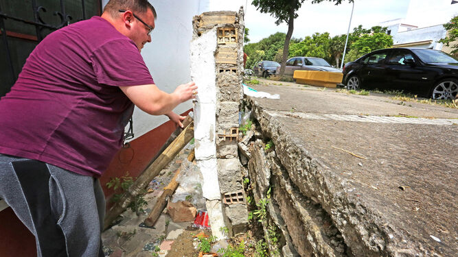 Francisco Díaz muestra el resto de muro que se mantiene 'en pie' junto a su casa con el apoyo de varios palos.