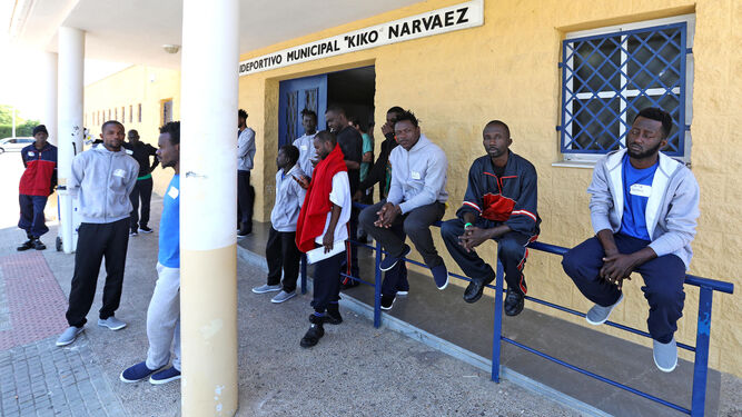 Los migrantes acogidos esperan en la puerta del polideportivo el traslado a sus destinos.