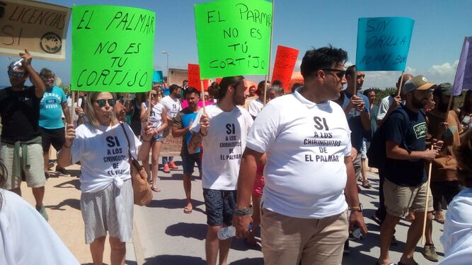 Manifestantes con pancartas en las que criticaban al alcalde de Vejer, ayer durante la protesta en El Palmar.