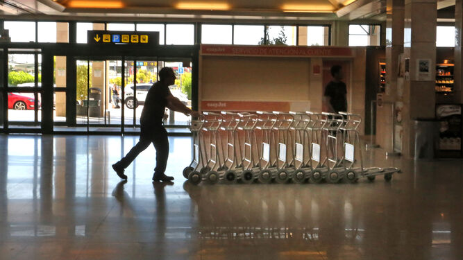 Un trabajador empuja los carros para los equipajes en la terminal de salidas del aeropuerto de Jerez.