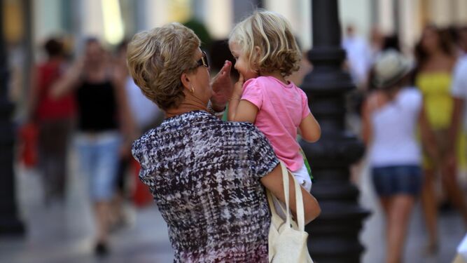 Una abuela lleva en brazos a su nieta.