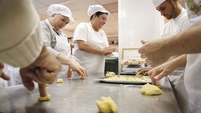 Voluntarios y usuarios de los servicios de Cáritas trabajando en la cocina.