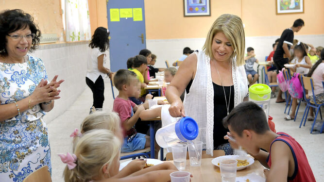 La alcaldesa sirve agua a unos niños, en una visita al comedor del CEIP Federico Mayo.