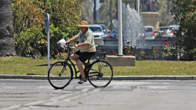 Un ciclista se protege del sol y el calor bajo su sombrero.