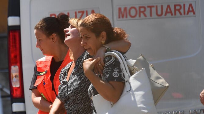 Familiares de las víctimas afectadas por el derrumbe del puente en Génova reciben ayuda médica a la salida del tanatorio de un hospital local.